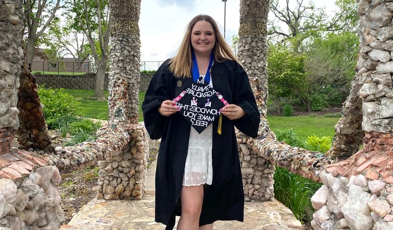 Macey in her graduation gown under the grotto