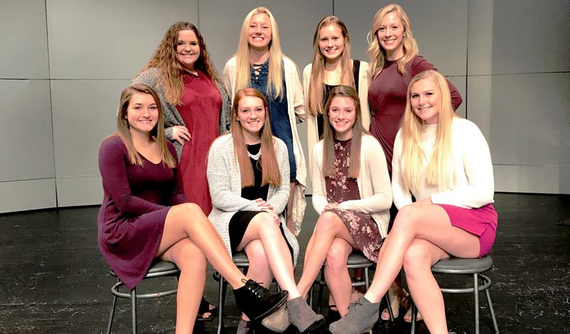 macey posing with a group of girls sitting in chairs in the McAuley auditorium