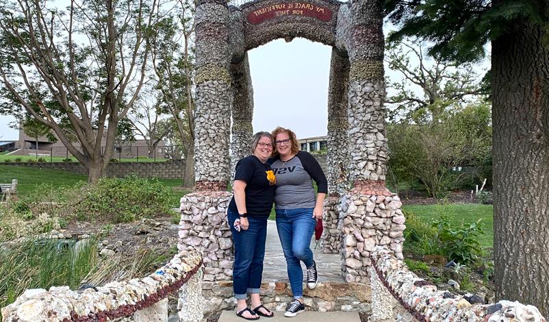 Kim Smith and Catherine standing beside the grotto in the greenspace in Mount Mercy University